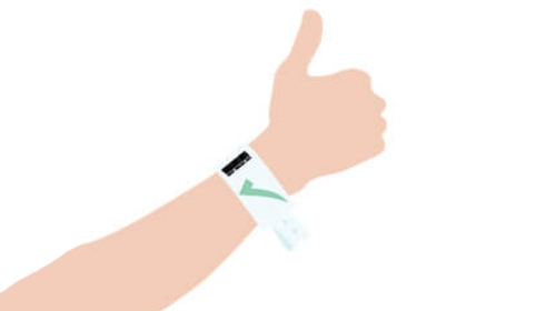 Person giving a thumbs-up while wearing a white medical ID/wristband on the wrist